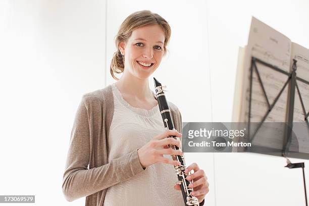 lächelnde frau hält klarinette - klarinette stock-fotos und bilder