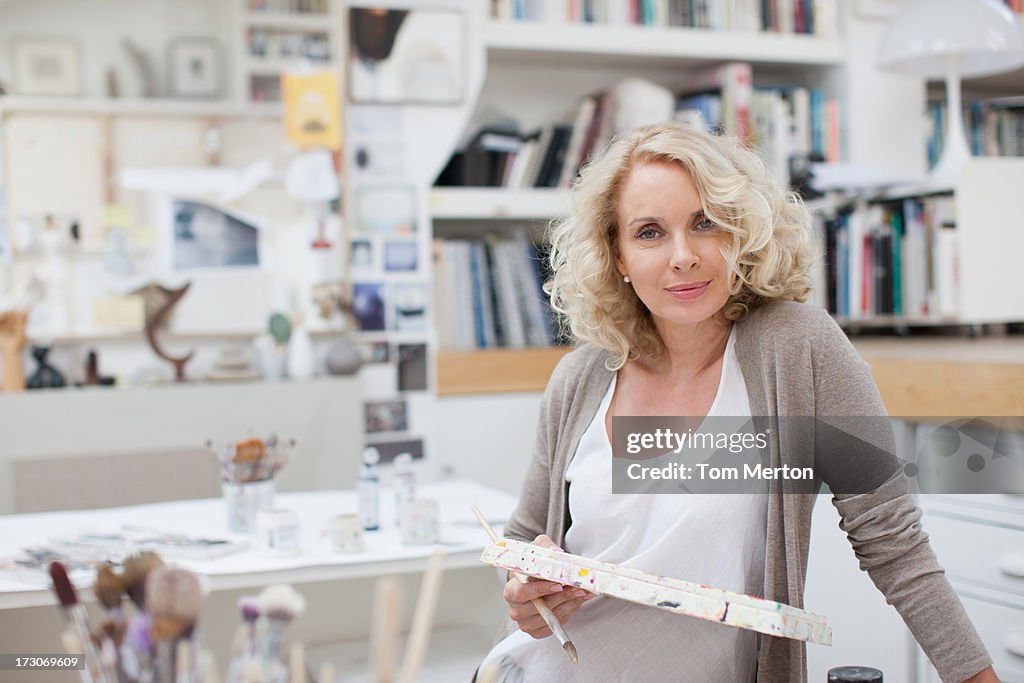 Woman holding paintbrush and palette in art studio