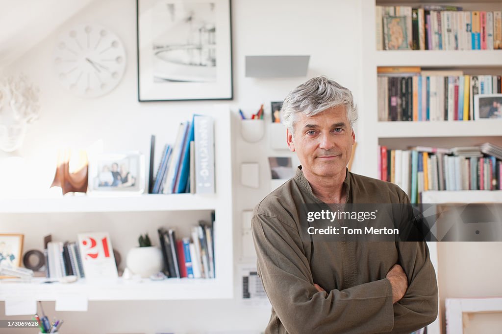 Smiling man with arms crossed in home office