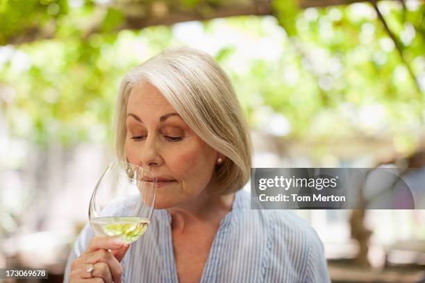 smiling woman drinking white wine - senior women wine stock pictures, royalty-free photos & images