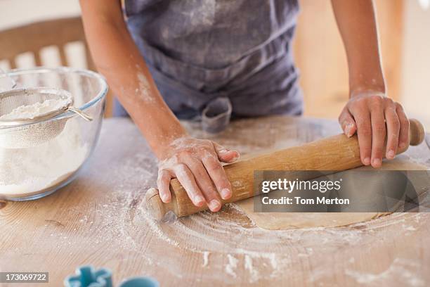 close up of woman rolling dough with rolling pin on kitchen counter - deegrol stockfoto's en -beelden