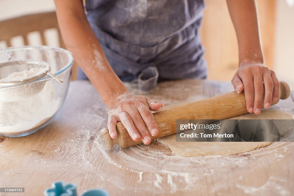 Close up of woman rolling dough with rolling pin on kitchen counter