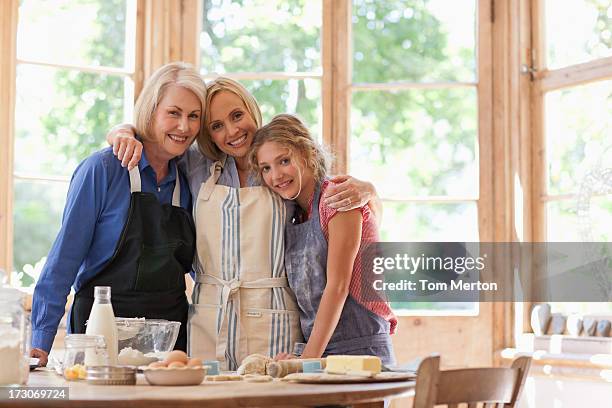 smiling multi-generation females hugging in kitchen - mother daughter baking stock pictures, royalty-free photos & images