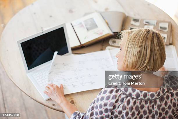 woman at table looking at genealogical tree - family tree stock pictures, royalty-free photos & images