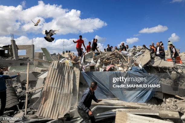 Pigeons fly as people inspect the remains of a destroyed building following Israeli bombardment in Khan Yunis in the southern Gaza Strip on October...