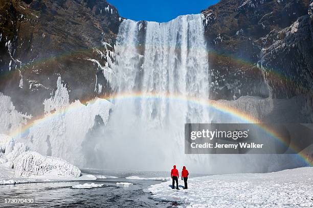 waterfall and rainbow with couple - iceland stock pictures, royalty-free photos & images