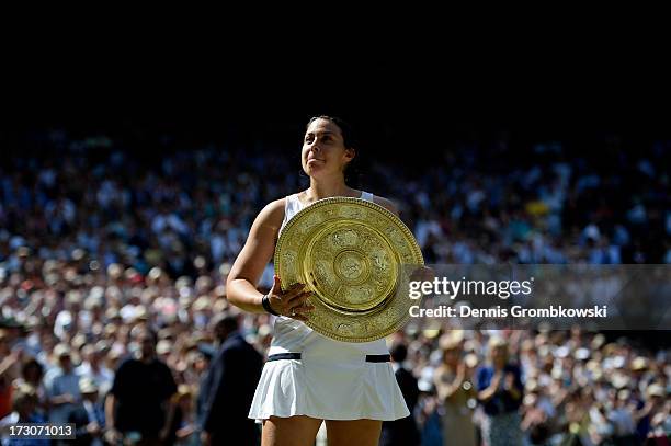 Marion Bartoli of France poses with the Venus Rosewater Dish trophy after her victory in the Ladies' Singles final match against Sabine Lisicki of...