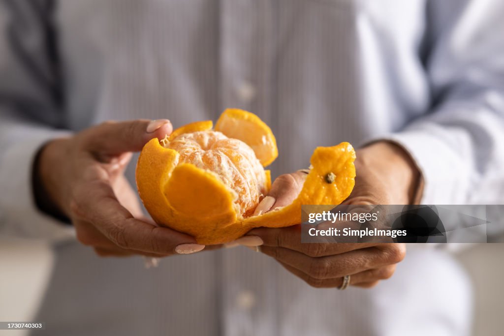 Close-up of a woman's hands peeling a tangerine.
