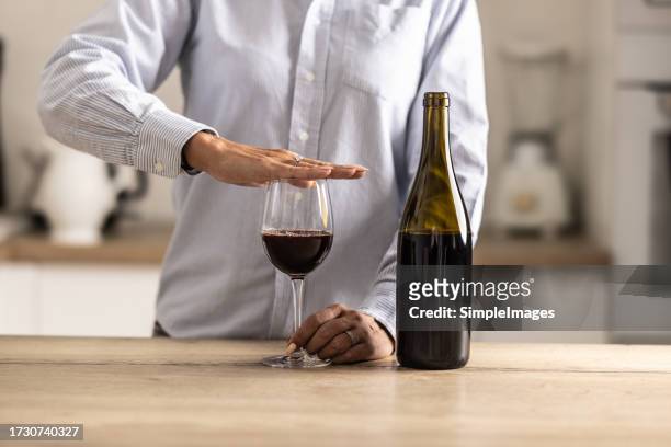 detail of a female hand holding palm over a glass of red wine as a sign of refusal to drink. - weigeren stockfoto's en -beelden