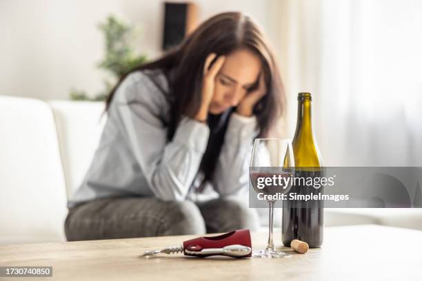 unhappy woman with bottle of wine sitting on couch and getting drunk - dronken stockfoto's en -beelden