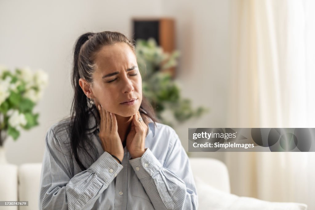 Women with thyroid gland problem with hands holding throat.