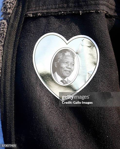Stickers featuring photos of former president Nelson Mandela are handed out to spectators at the gates during the 2013 Vodacom Durban July at...