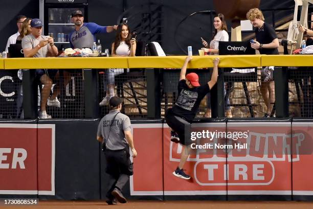 Fan attempts to climb the outfield wall to avoid security in the seventh inning during Game Three of the Division Series between the Los Angeles...