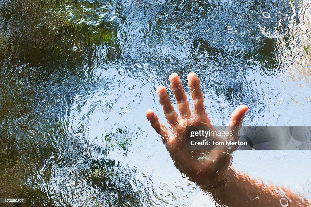 Hands reaching out behind glass