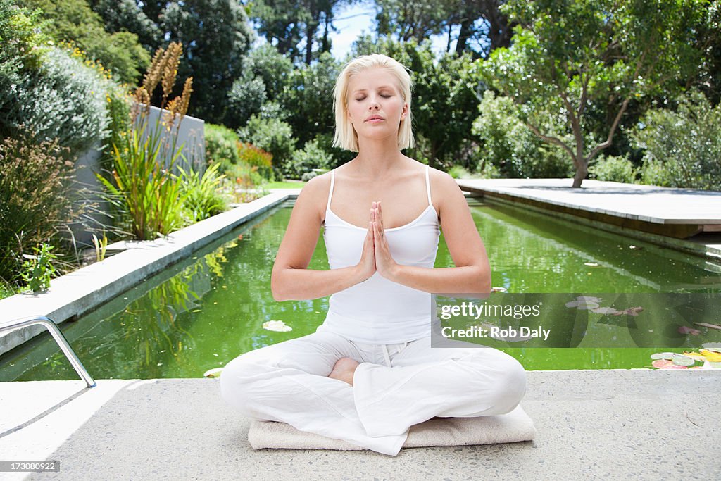 Frau üben yoga in der Nähe des Swimmingpools