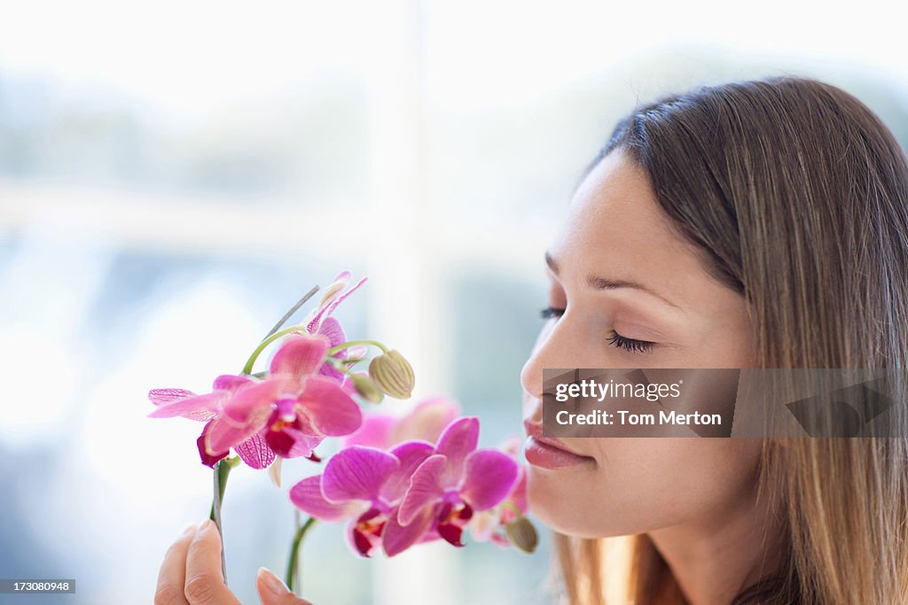 Woman with eyes closed smelling orchid