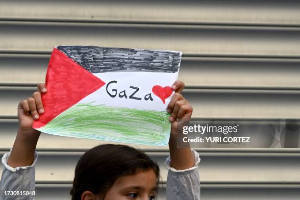 Palestinian girl holds up a hand drawn picture of the national flag raise their hands as they protest in the city of Ramallah, in the occupied West...