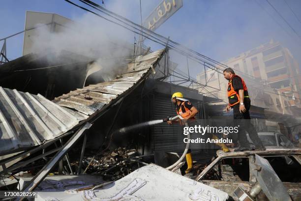 Firefighters and residents try to put out the fire at a bakery shop which was destroyed after Israeli airstrikes at Nuseirat Refugee Camp in Deir al...