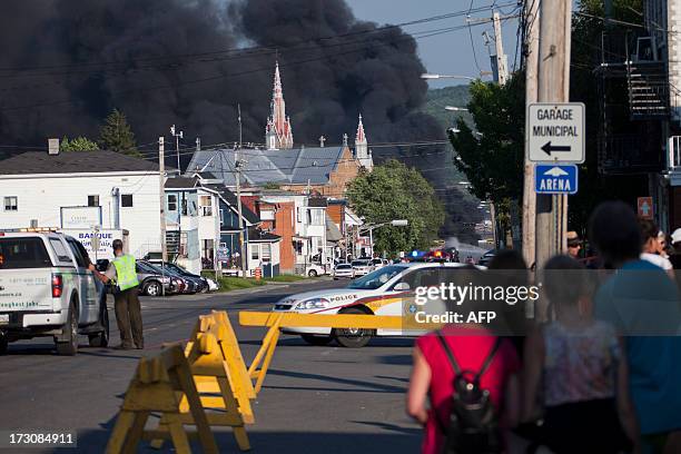 Residents watch rising smoke after a freight train loaded with oil derailed in Lac Megantic in Canada's Quebec province on July 6 sparking explosions...