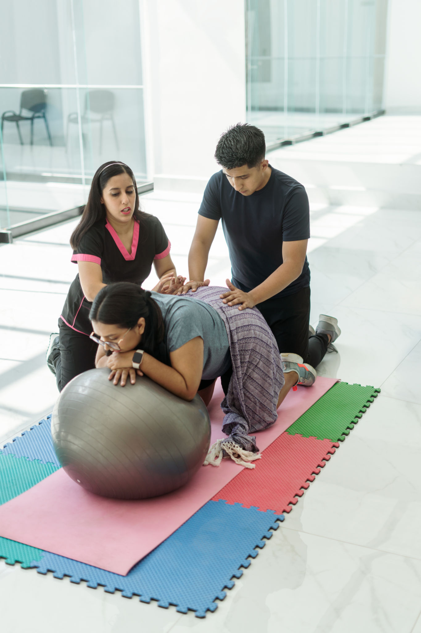 Instructor explains to young man how to help with exercises that provide comfort to his pregnant wife Instructor explains to young man how to help with exercises that provide comfort to his pregnant wife