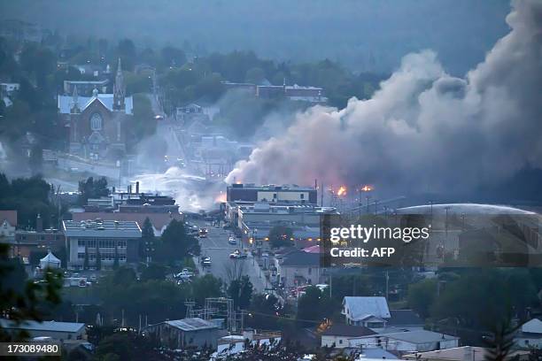 Firefighters douse blazes after a freight train loaded with oil derailed in Lac-Megantic in Canada's Quebec province on July 6 sparking explosions...