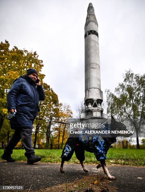 Woman walks her pet in front of a Soviet R-9A intercontinental ballistic missile next to the central Museum of Russia's Armed Forces in Moscow on...