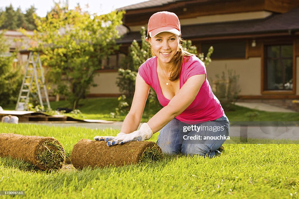 Woman Rolling out Lawn Turf