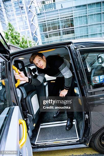 young man leaving london cab arrived at canary wharf - london taxi stock pictures, royalty-free photos & images
