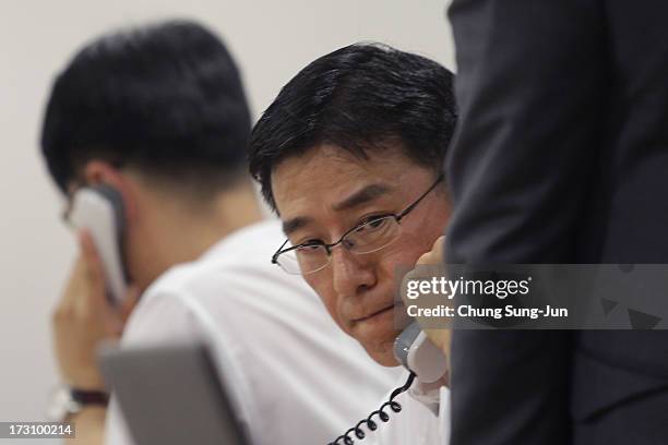 Asiana Airline employees talk on the phone with family members of passengers on Asiana Airlines Flight 214 which crashed as Asiana Airlines set up an...