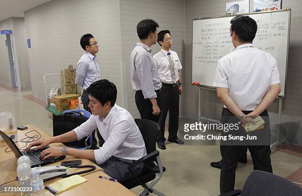 Asiana Airlines employees talk as the airline man an emergency room and phone line at the Incheon International Airport on July 7, 2013 in Incheon,...