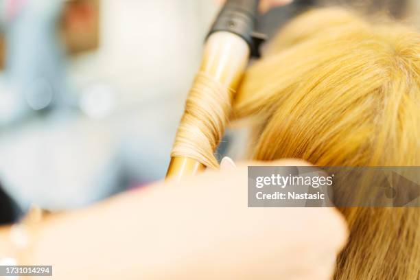 nahaufnahme eines friseurs mit einem lockenstab im salon - lockenstab stock-fotos und bilder