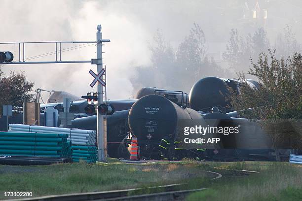 Firefighters inspect the wreckage on July 7, 2013 of a freight train loaded with oil that derailed July 6 in Lac-Megantic in Canada's Quebec...