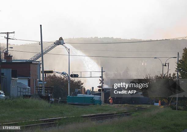 Firefighters continue to pour water July 7, 2013 on the wreckage of a freight train loaded with oil that derailed July 6 in Lac-Megantic in Canada's...