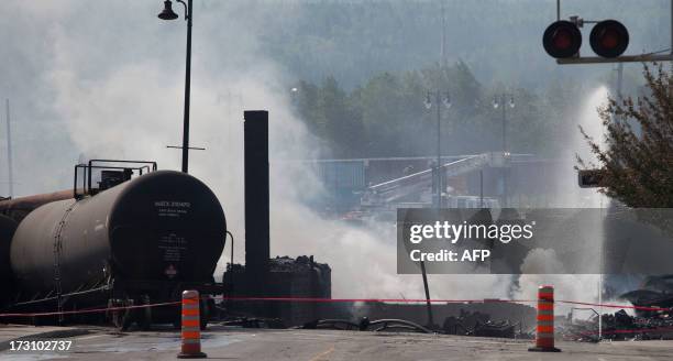 Wreckage continues to burn on July 7, 2013 after a freight train loaded with oil derailed July 6 in Lac-Megantic in Canada's Quebec province,...