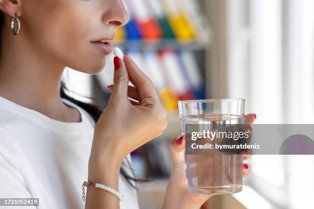 woman taking tablet with glass of fresh water. - prevenção de doenças imagens e fotografias de stock
