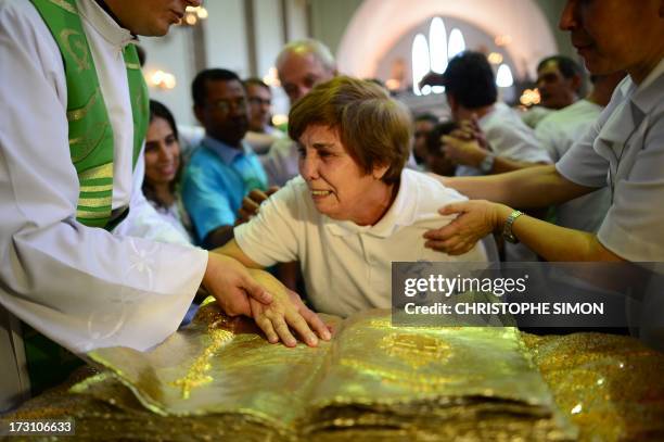 An old woman is assisted to touch a relic during a mass officiated by Cardinal Stanislaw Rylko to celebrate the arrival in Brazil of the relics of...