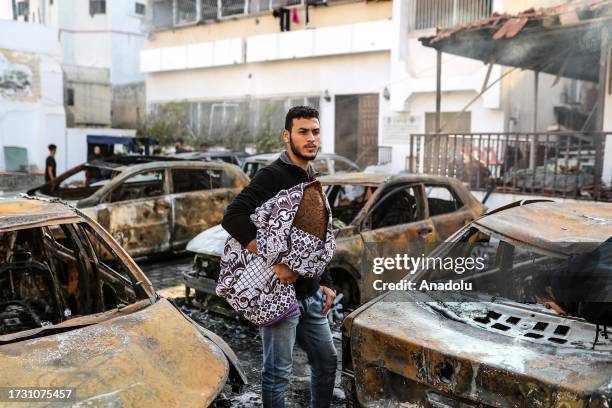 Man tries to collect usable belongings amid wreckage of vehicles after Al-Ahli Baptist Hospital was hit in Gaza City, Gaza on October 18, 2023....