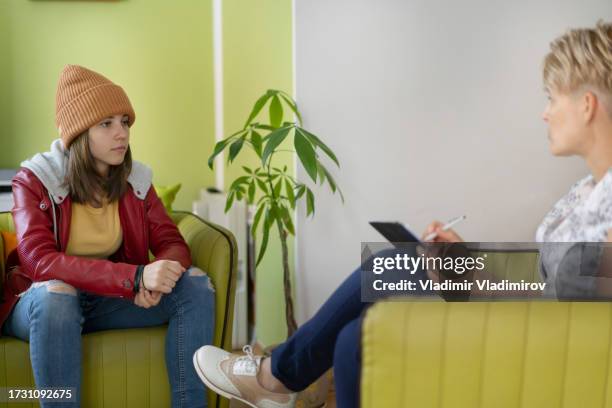 an upset girl sitting sad in front of a female psychologist - child eating disorder stock pictures, royalty-free photos & images