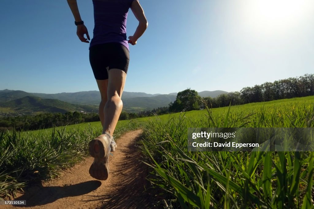 Woman running on trail thru meadow