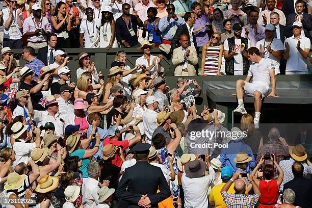 Andy Murray of Great Britain climbs down after celebrating in his player's box with friends, family and members of his coaching team following his...