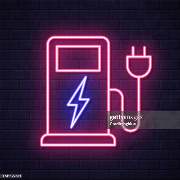 charging stations for electric vehicles. glowing neon icon on brick wall background - plug in night light stock illustrations