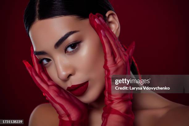 photo of asian young lady femme fatale touch face lace gloves visage shoulders off isolated dark red color background - femme glamour stock pictures, royalty-free photos & images