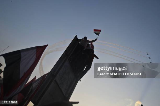 Egyptian jet fighters trail smoke as they fly over Tahrir Square, in Cairo, on July 7 as tens of thousands of people staged a show of force in Tahrir...