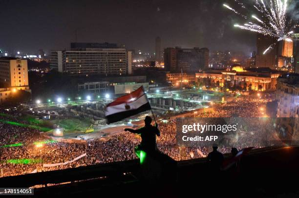 Egyptians wave the national flag on a building rooftop on July 7, 2013 as hundreds of thousands flood Cairo's landmark Tahrir square to demontrate...