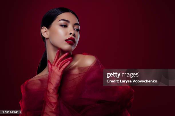 photo of asian young woman femme fatale touch neck tease sexual desire shoulders off isolated dark red color background - femme glamour stock pictures, royalty-free photos & images