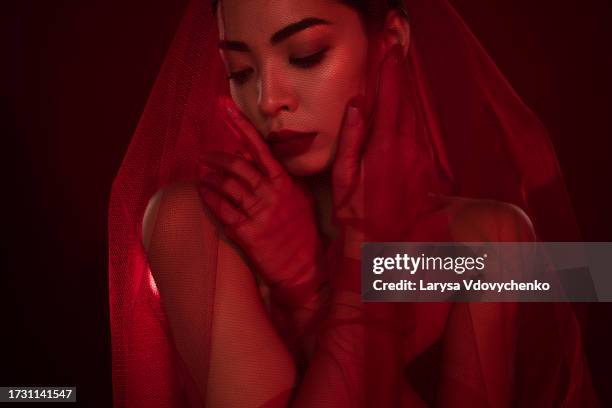 photo of asian young woman femme fatale touch face teasing sexy bride shoulders off isolated dark red color background - veil face stock pictures, royalty-free photos & images