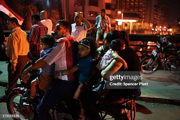 Group of people ride a motorcycle as Egyptians celebrate into the night on a bridge near Tahrir Square following a massive rally against ousted...