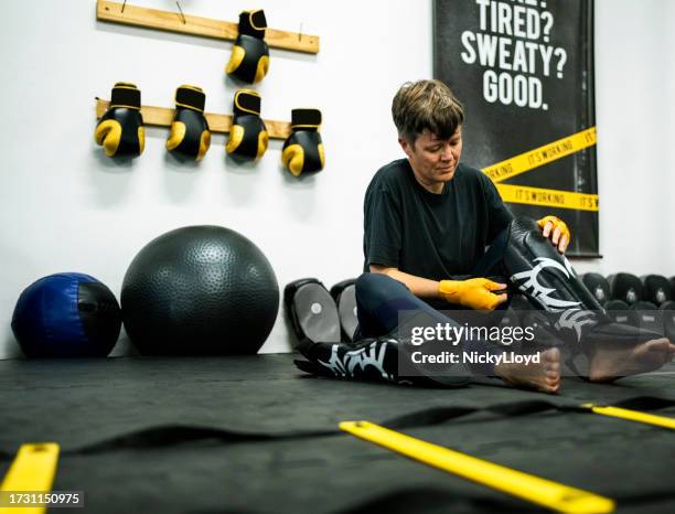 woman wearing shin guards and getting ready to muay thai workout at gym - shin guard stock pictures, royalty-free photos & images