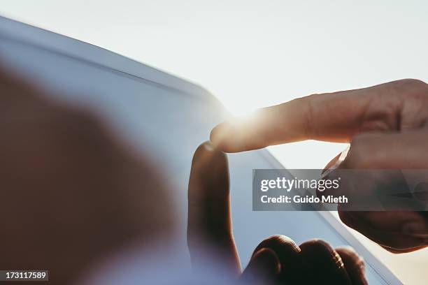 finger pointing on tablet pc screen - ipad close up imagens e fotografias de stock