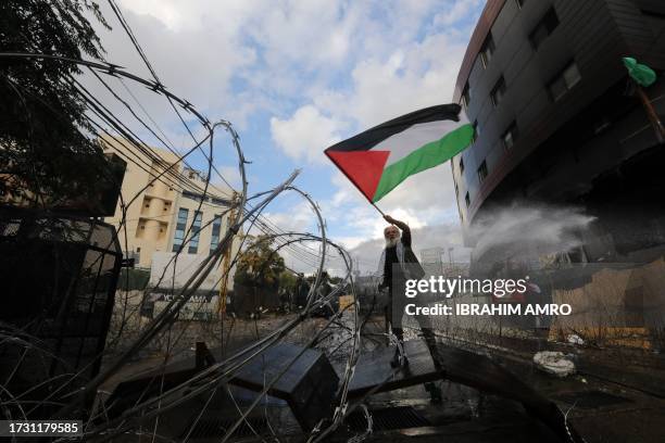 Man waves a Palestinian flags as Lebanese security forces clash with protesters outside the US Embassy in Awkar east of Beirut, during a...